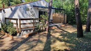 Ein modernes Haus mit einer Holzdachterrasse, einem überdachten Sitzbereich im Freien und einem Garten mit Holzzaun und Pflanzen.
