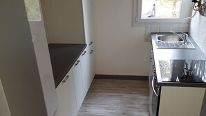 Eine kleine Küche mit Spüle, Herd und Schränken.