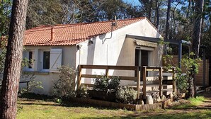 Ein kleines Haus mit rotem Ziegeldach, umgeben von Bäumen und einem Rasen.
