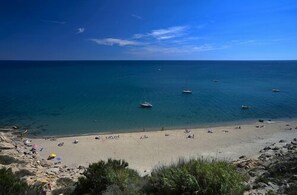 Une plage avec une eau d’un bleu limpide, des bateaux et des gens qui se détendent.