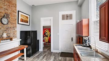 A kitchen with a black refrigerator, wooden bench, and a clock on the wall.