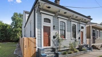 A two-story house with a front porch, a wooden gate, and a small garden area.