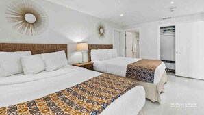 Habitación de hotel con dos camas, un espejo grande y un armario.