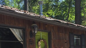 Ein Holzbauten mit grüner Tür, einem Kranz und einem Schornstein.