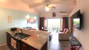 A kitchen with a stove, sink, and a dining area with a table and chairs.