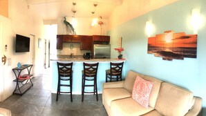 A compact living space with a kitchenette, a sofa, and a dining area with three chairs.