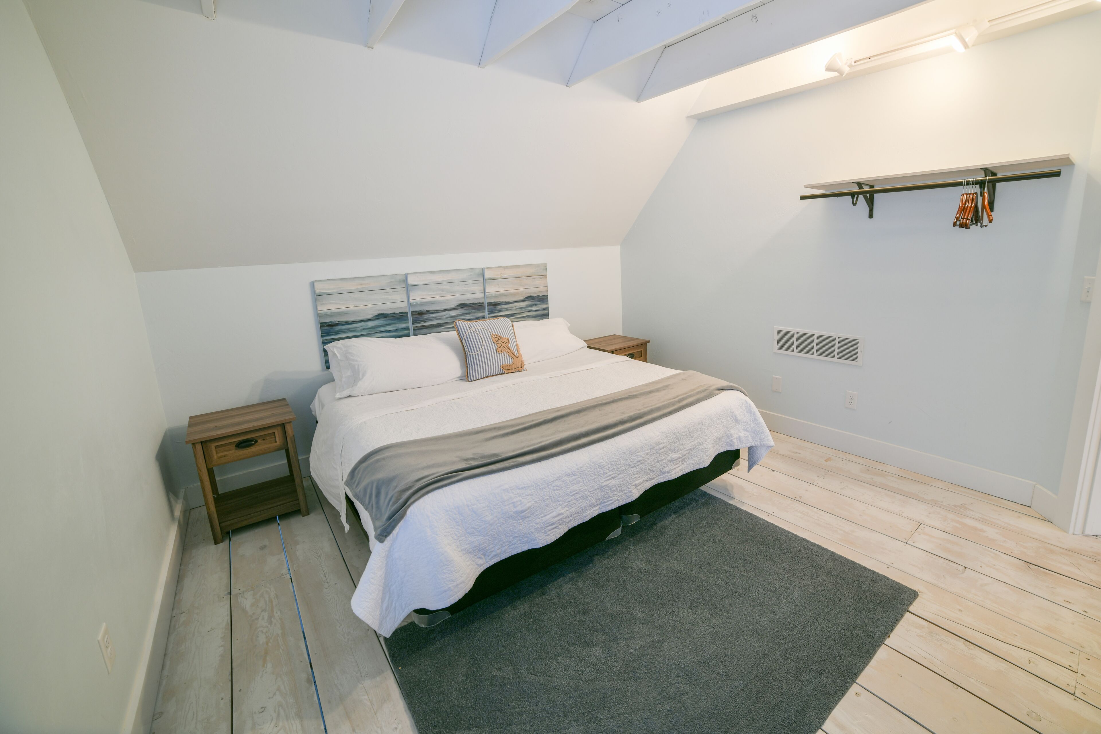A bedroom with a bed, nightstands, a headboard, a ceiling fan, a wall-mounted shelf, and a window.