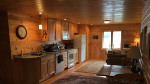 L’intérieur d’une cabane en bois comprend une cuisine, un coin repas et une grande fenêtre.