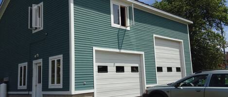 A two-story house with a garage, a driveway, and a car parked in front.