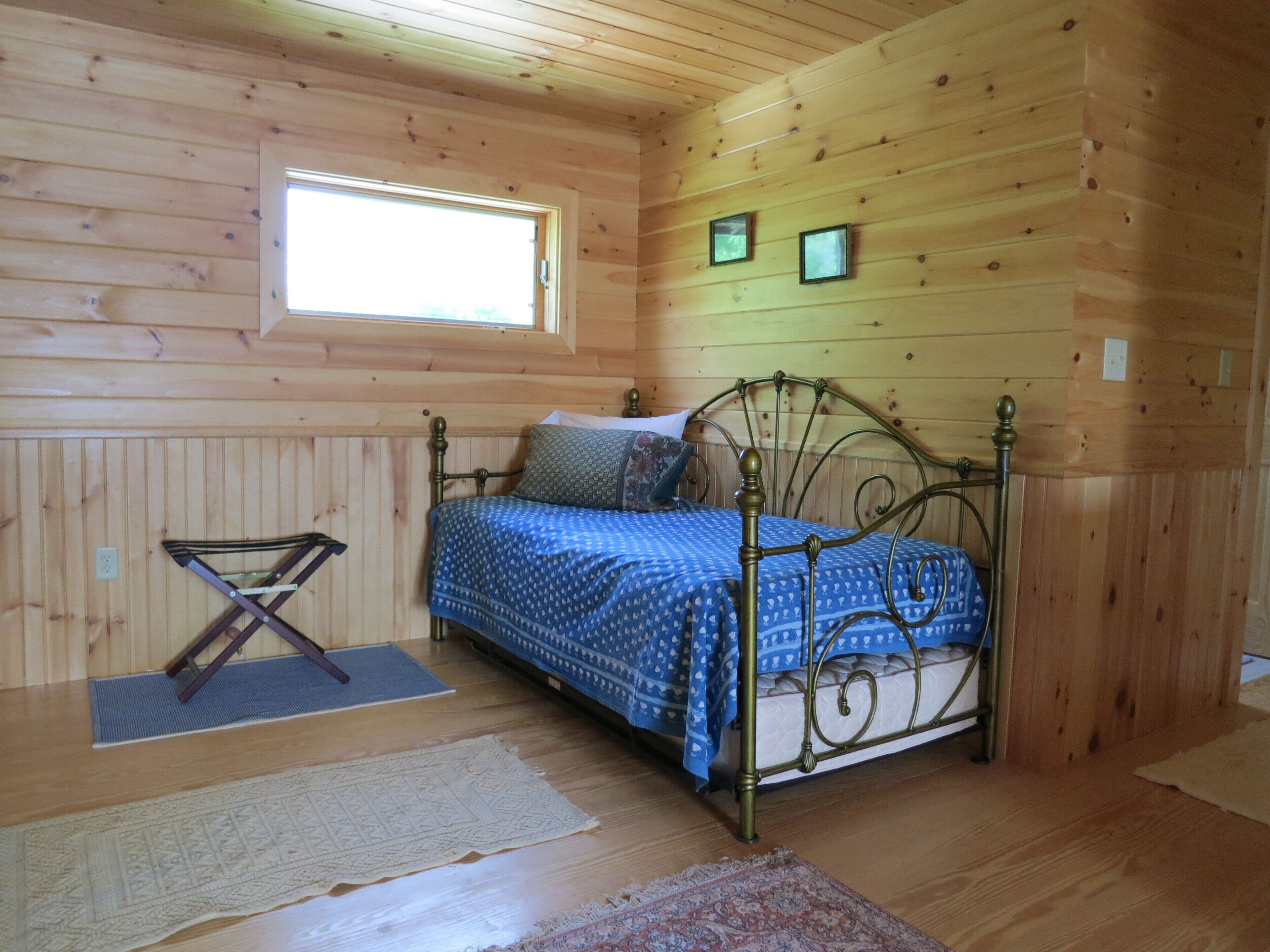 Une pièce dans un chalet en bois, avec un lit, une fenêtre et une petite table.