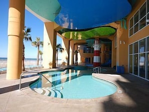 Relax by the ocean-view pool, surrounded by a shaded area and lounge chairs.