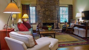 A cozy living room with a stone fireplace, comfortable seating, and a television.