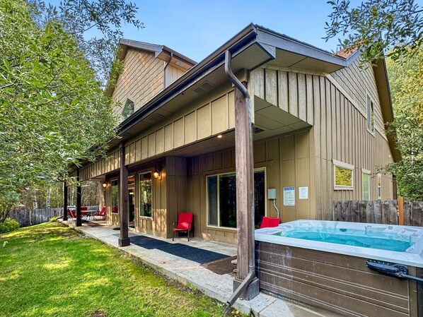 Una casa con porche cubierto, jacuzzi y patio trasero cercado.