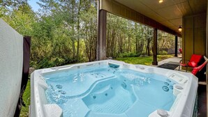 Una vasca idromassaggio con un pontile in legno e un’area coperta, immersa nel verde.