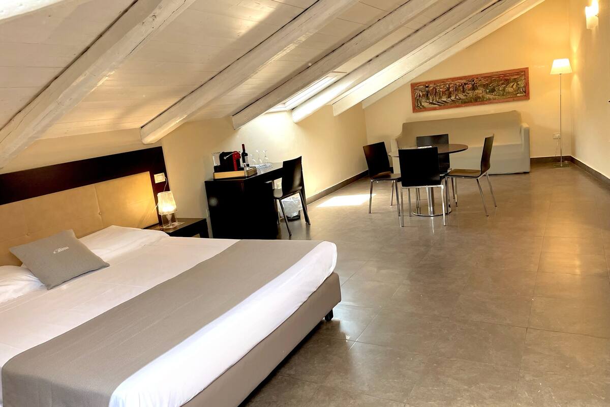 A hotel room with a bed, desk, chairs, and a dining table.