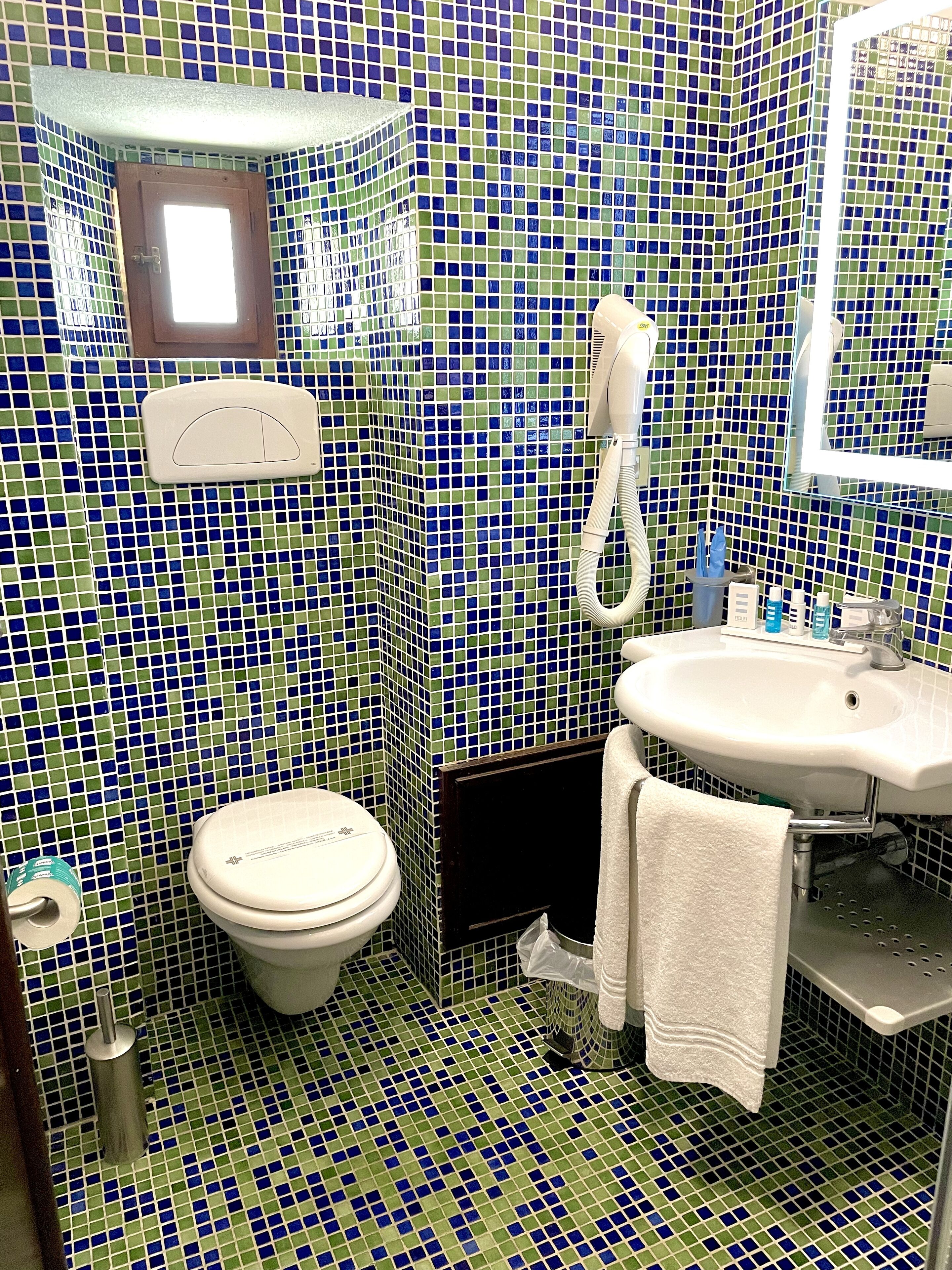 A bathroom with a toilet, sink, and mirror.