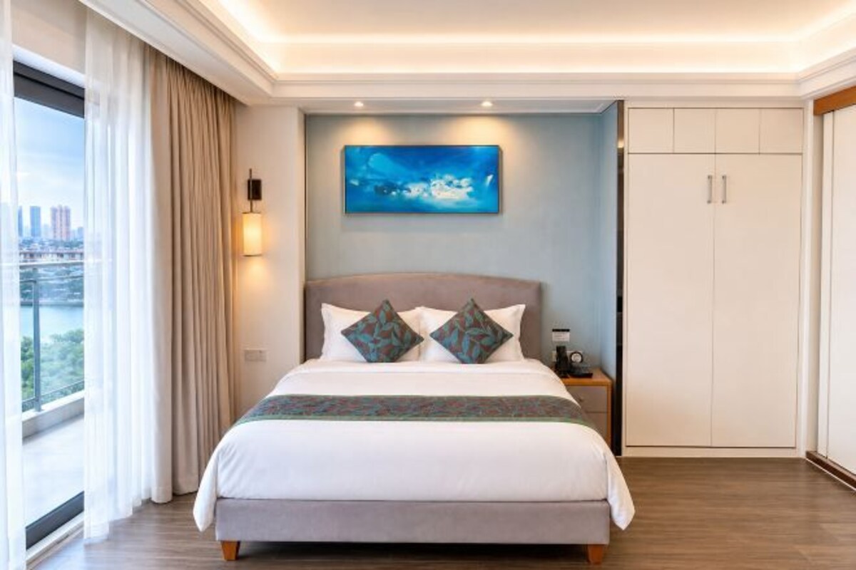 A bedroom with a large bed, a nightstand, a painting, and a wardrobe.