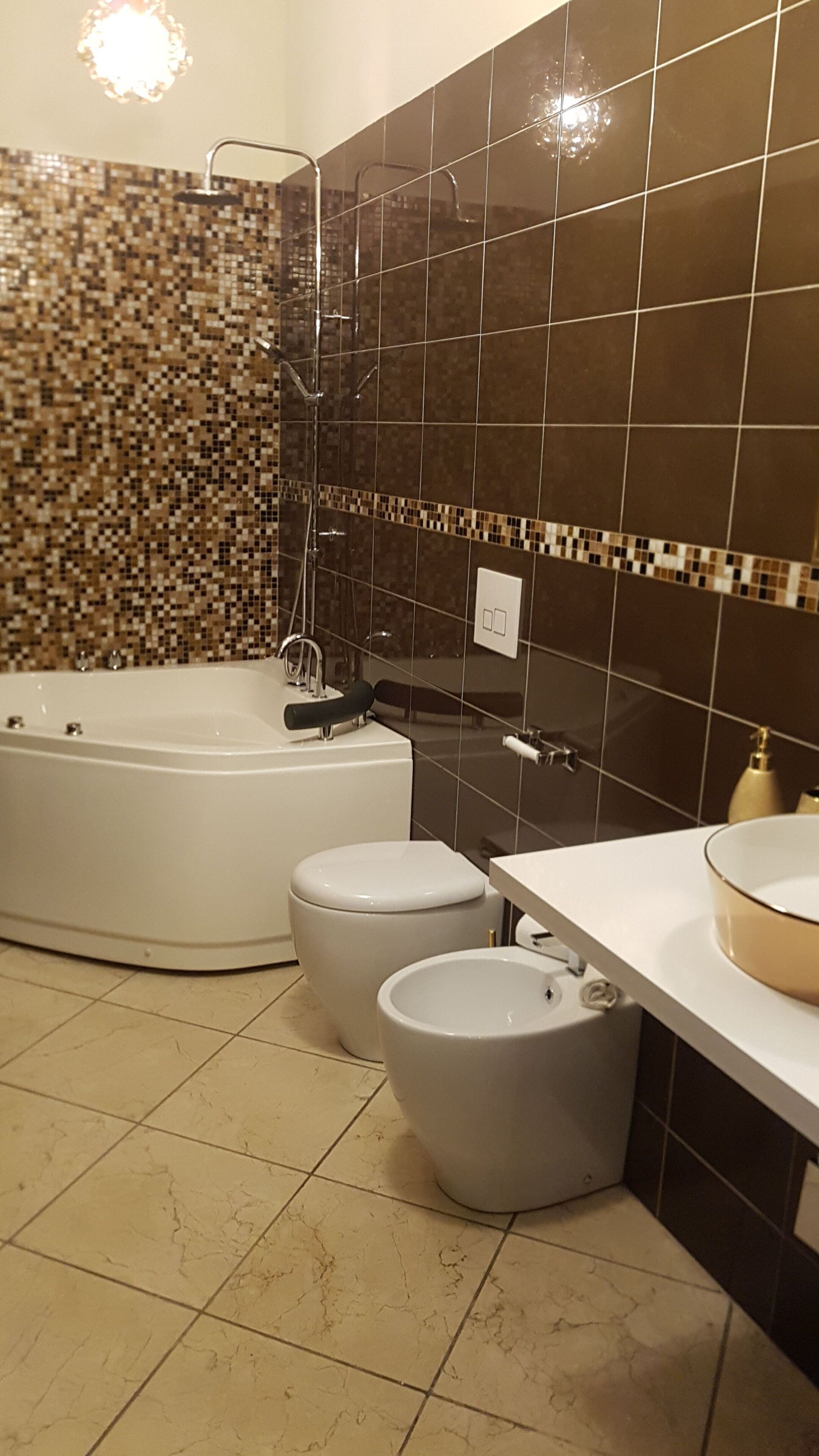 A bathroom with a bathtub, two toilets, and a sink.