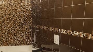 A bathroom with a bathtub, two toilets, and a sink.