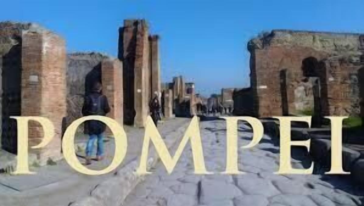 Une structure romaine antique, avec des arches et des colonnes en pierre, portant l’inscription « POMPEI ».