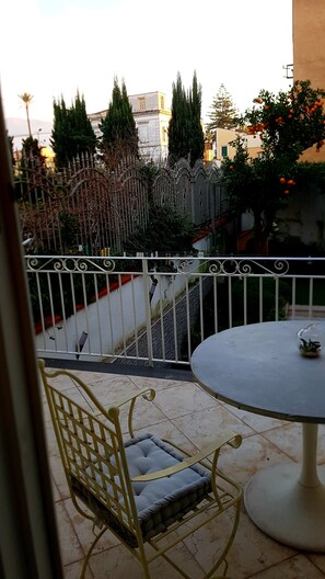 Ein Balkon mit Metallgeländer, einem runden Tisch und einem gepolsterten Stuhl.