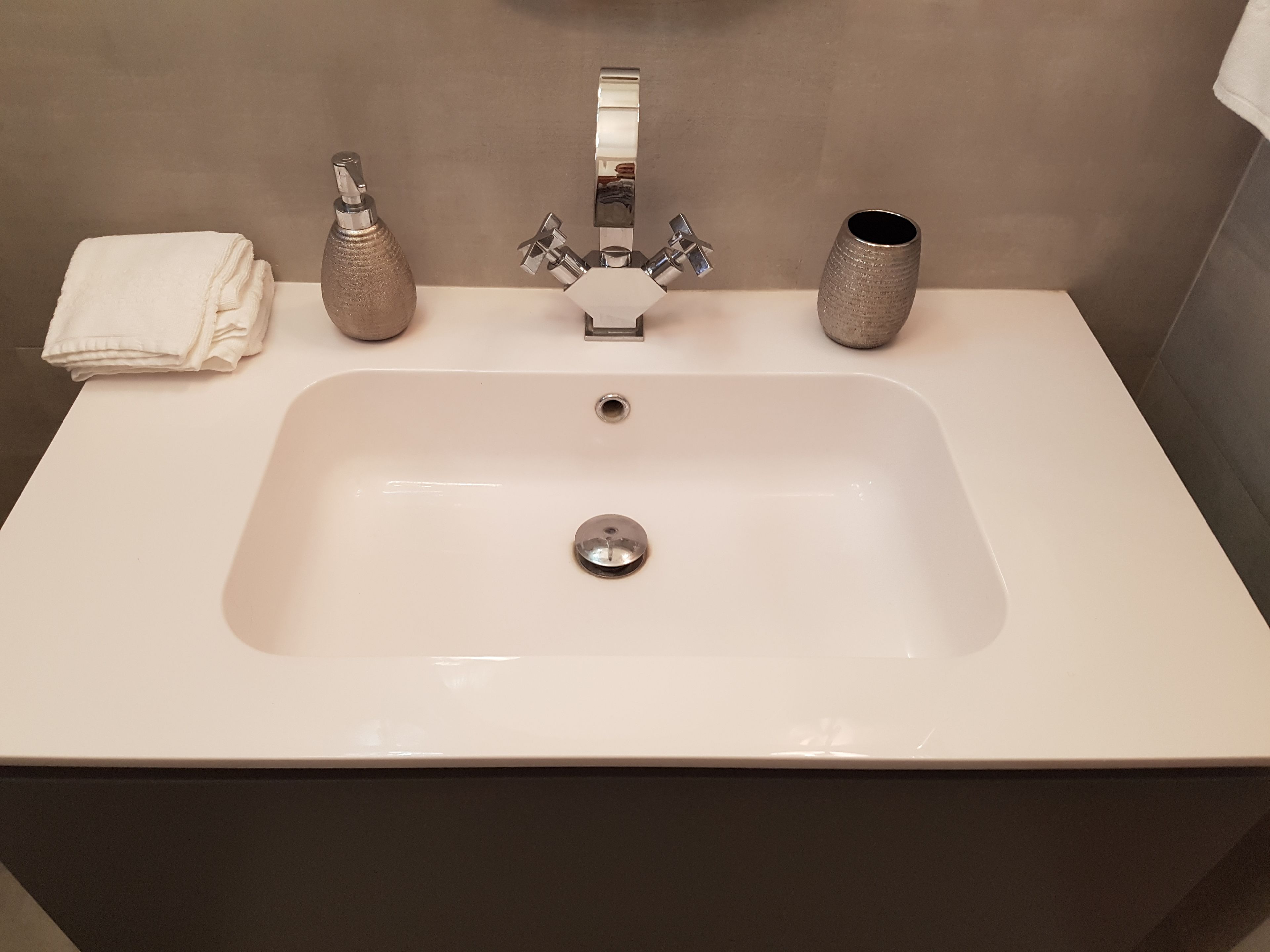 Un lavamanos de baño con un grifo moderno, una toalla y dos jarrones decorativos.