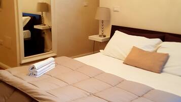 A hotel room with a bed, a nightstand, a lamp, and a mirror.