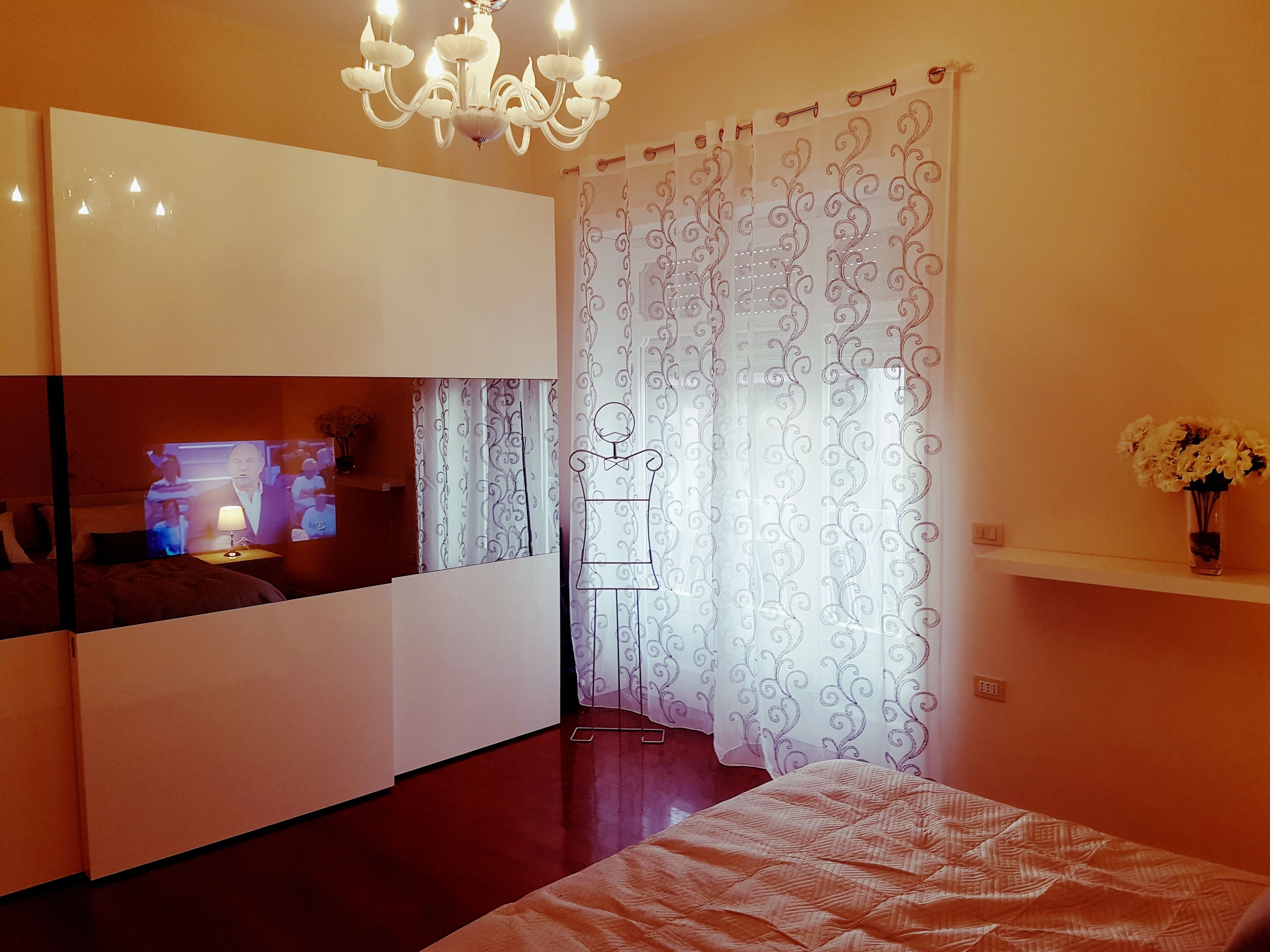 Une chambre moderne avec un lit, une télévision, un lustre et un rideau décoratif.