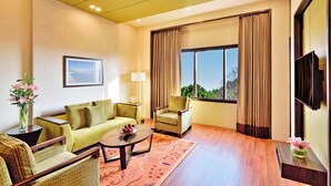 A modern living room with a sofa, armchairs, a coffee table, and a TV. - Four Points By Sheraton Srinagar (Srinagar)