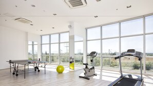 A spacious gym with a treadmill, exercise bike, and a table tennis table. - Ramada Hotel & Suites by Wyndham Edirne (Edirne)