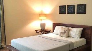 Ein Schlafzimmer mit einem Bett, einem Nachttisch mit Lampe und drei gerahmten Bildern an der Wand.