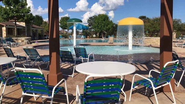 Ein Poolbereich mit Liegestühlen, einem Tisch und einer Wasserspiels.