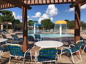 A pool area with lounge chairs, a table, and a water feature.