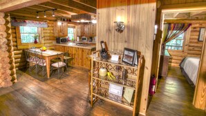 A log cabin interior with a dining area, kitchen, and a bedroom. - Sitting on 20 beautiful acres, totally secluded, Just 6 miles from Helen, GA! (Sautee Nacoochee)