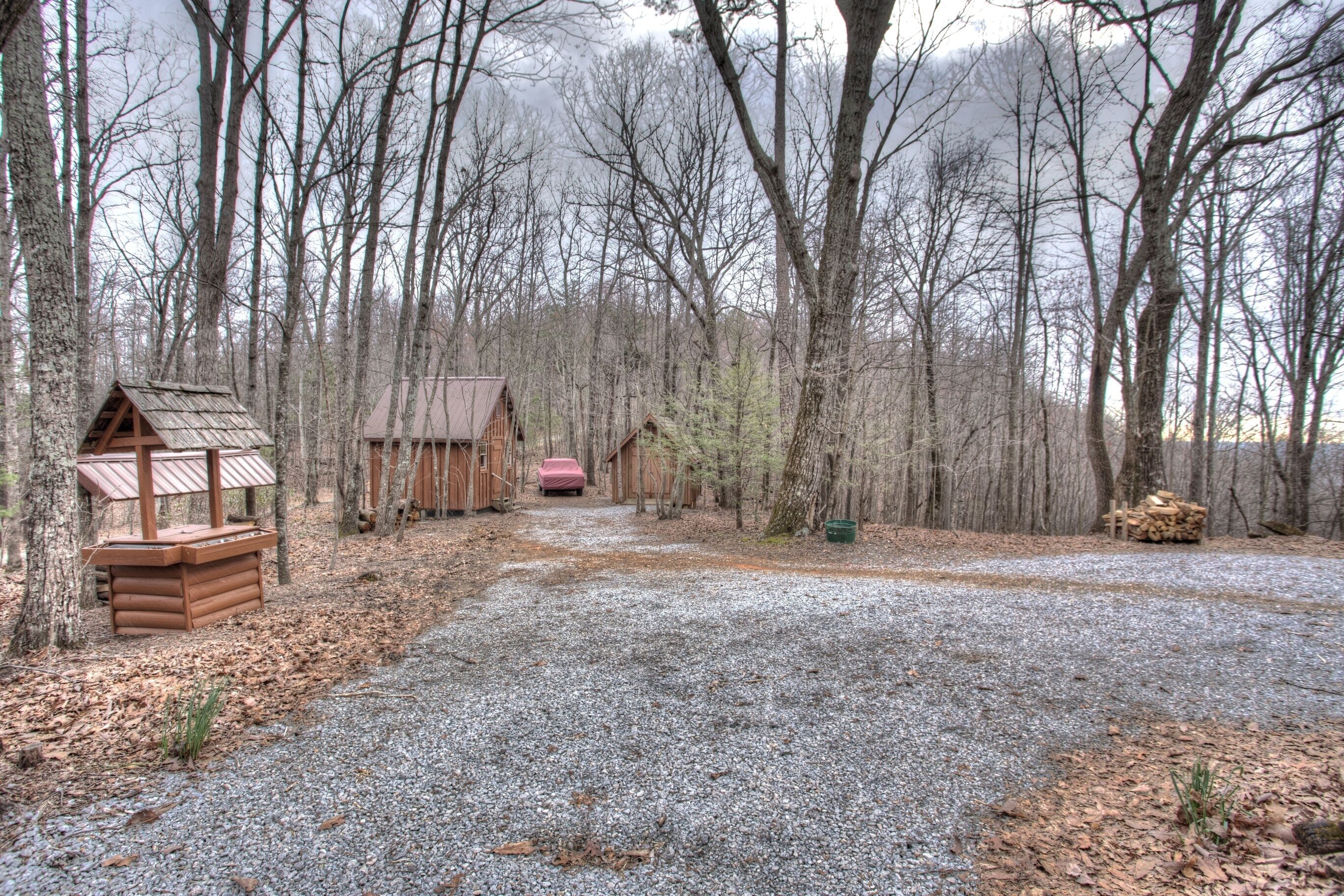A gravel path leading to a rustic cabin area surrounded by trees.