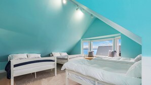 Une chambre avec deux lits, une fenêtre donnant sur un beau paysage et un plafond en pente.