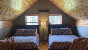 A cozy attic bedroom with two beds, wooden ceiling, and two windows. - Hidden Gem In East Glacier Park (East Glacier Park Village)