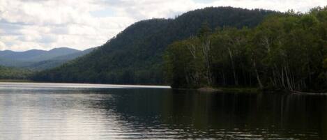 Un lago tranquilo con una colina boscosa al fondo.