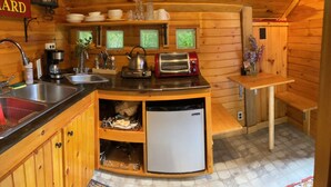 A compact kitchen with a sink, a coffee maker, a toaster, and a small refrigerator. - GLAMP RICHARD ON ADIRONDACK FLOWER FARM (North River)