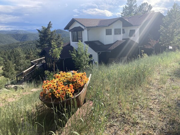 Una casa con vista a montañas, una terraza de madera y una maceta.