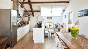 A spacious kitchen with wooden beams, a central island, and a dining area with a wooden table and chairs. - Great Family Loft apartment (Haarlem)