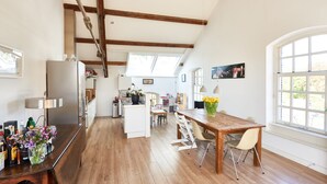 A spacious kitchen with wooden beams, a dining area with a wooden table and chairs, and a large window providing natural light. - Great Family Loft apartment (Haarlem)