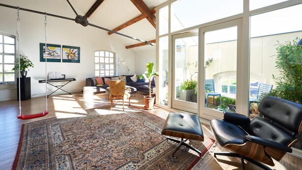 A spacious living room with a large window, a swing, a sofa, and a coffee table. - Great Family Loft apartment (Haarlem)