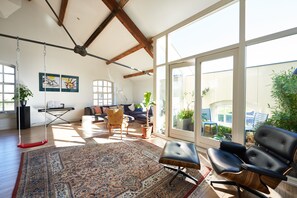 A spacious living room with a large window, a swing, a sofa, and a coffee table. - Great Family Loft apartment (Haarlem)