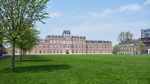 A large, historic building with a symmetrical facade, a central clock tower, and a well-maintained lawn in front. - Great Family Loft apartment (Haarlem)
