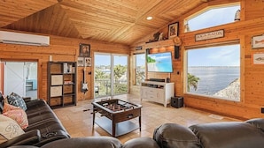 A wooden interior with a foosball table, a TV, and a view of the ocean. - The Boat House · Riverfront · Heated Pool & Spa · Tiki Bar · Sleeps 10 (Cape Coral)