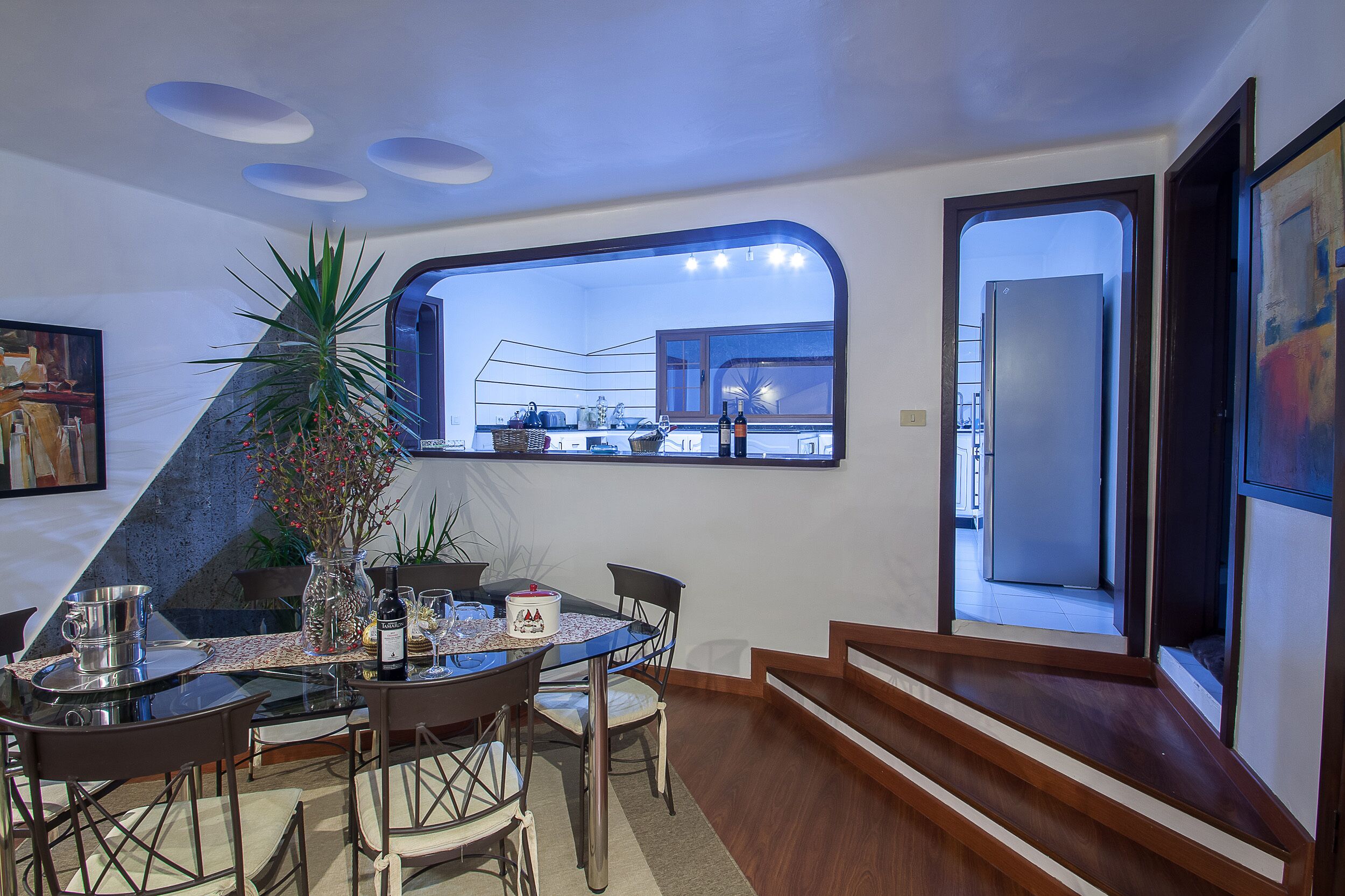 A dining area with a large window, a potted plant, and a table set for four.