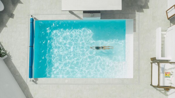 An aerial view of a rectangular swimming pool with clear blue water, surrounded by a tiled deck. - Villa with private Jacuzzi, pool and amazing sea views in a quiet area (Puerto del Carmen-La Asomada-Lanzarote)