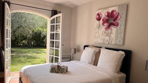 Een slaapkamer met een bed, een groot raam en een schilderij van bloemen.
