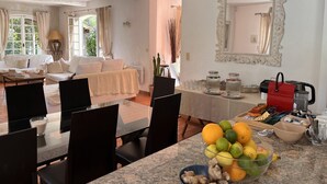 Een eethoek met een marmeren tafel, stoelen en een schaal fruit.